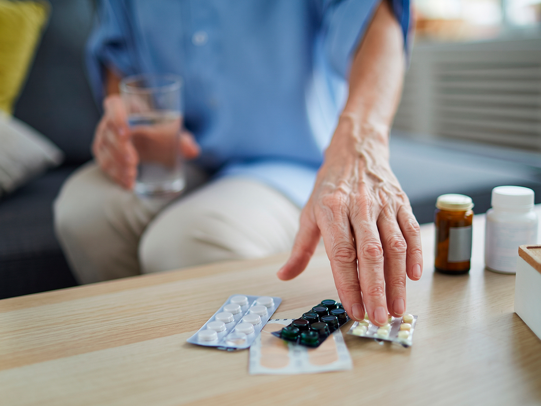 Pessoa idosa organizando diferentes medicamentos sobre uma mesa